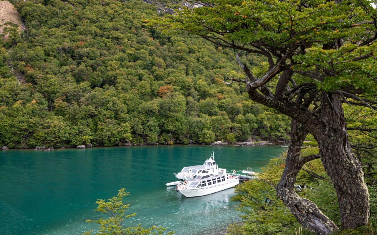 Catamarã ancorado em lago de águas turquesa, na Patagônia, tipo de embarcação usada em travessias até o bosque