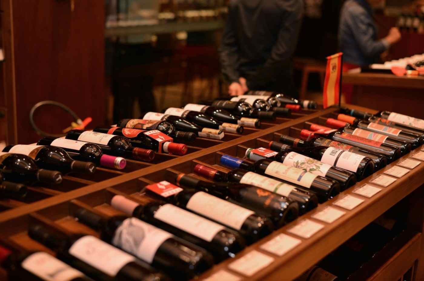 Garrafas de vinho dispostas em expositor de madeira de uma loja especializada, ilustrando a ampliação do consumo no país