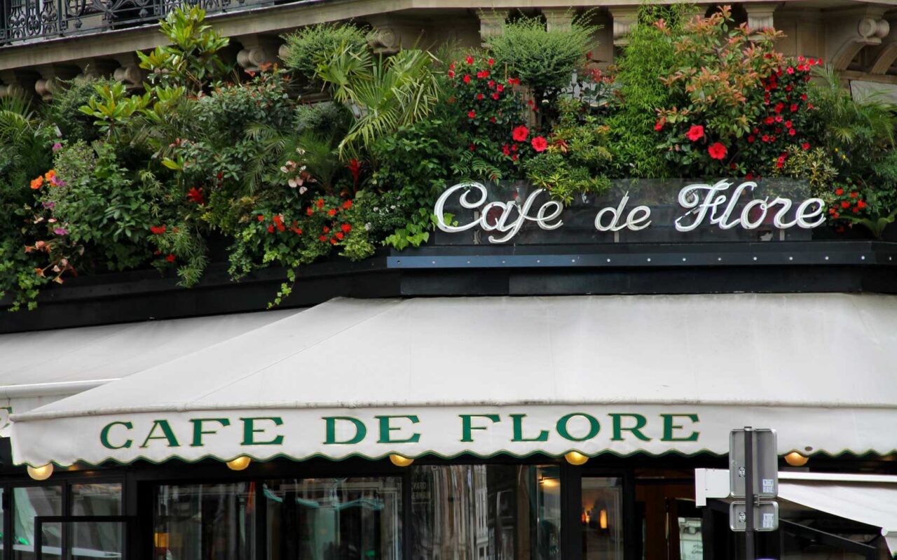 Sob o letreiro iluminado, a esquina mais disputada de Saint-Germain se cobre de folhagem e flores vermelhas
