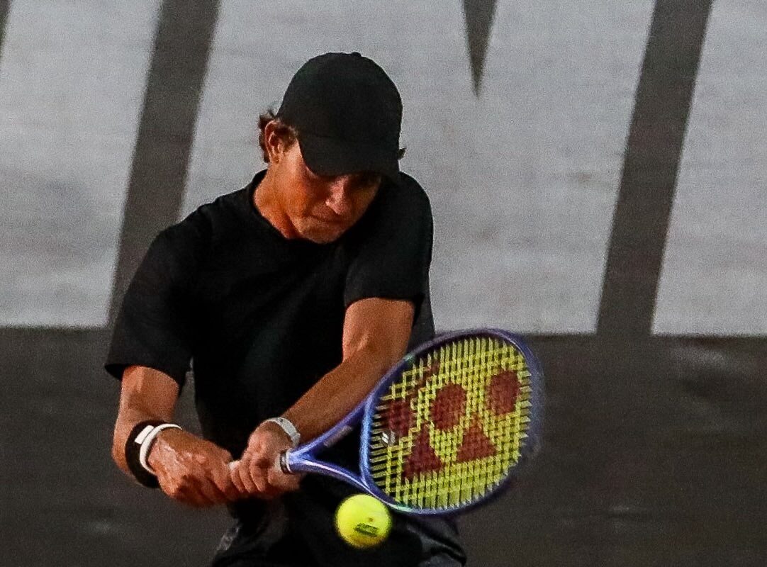 Tenista rebate de backhand em quadra de saibro durante o Maceió Tennis Experience, torneio da ITF em Maceió