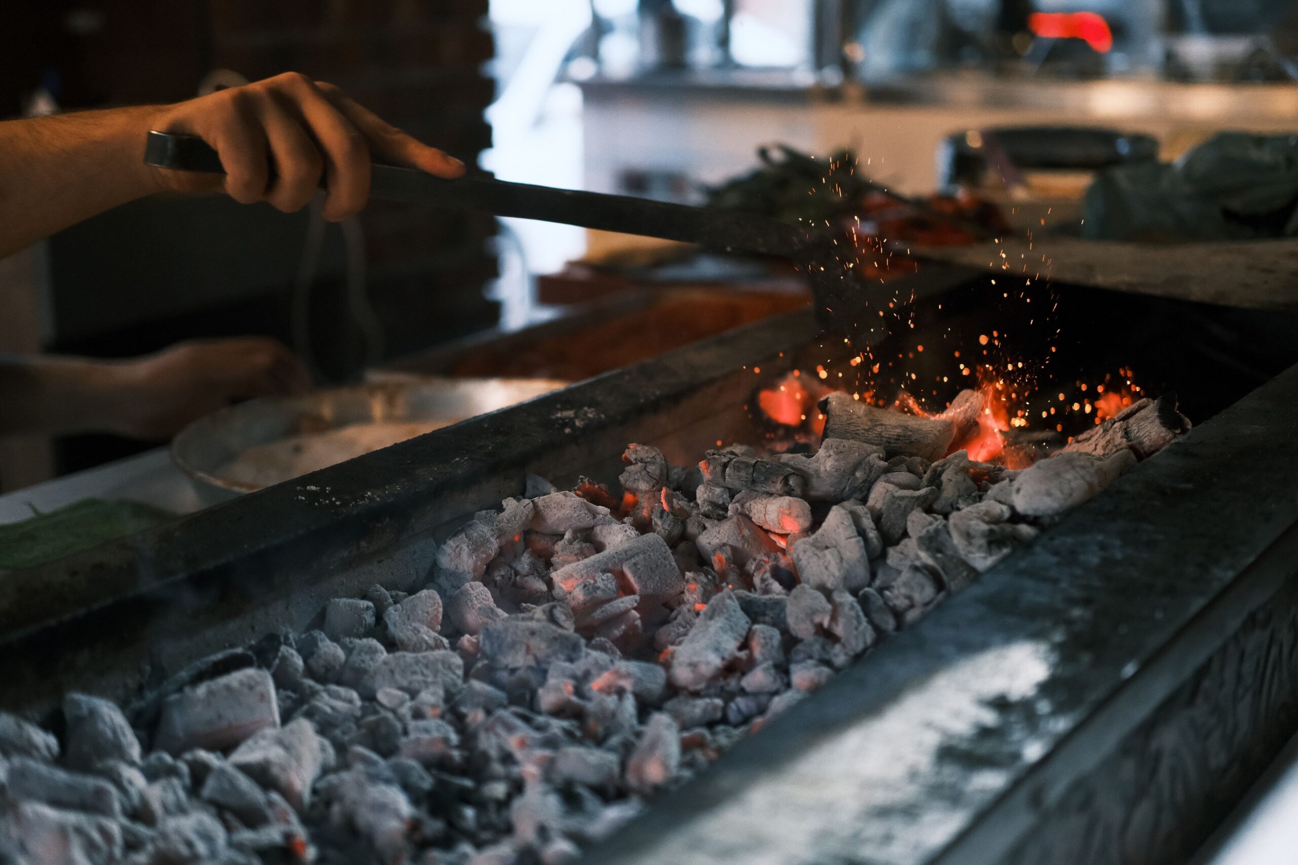 Antes de qualquer panela, é o carvão em ponto de brasa que dita o ritmo da cozinha