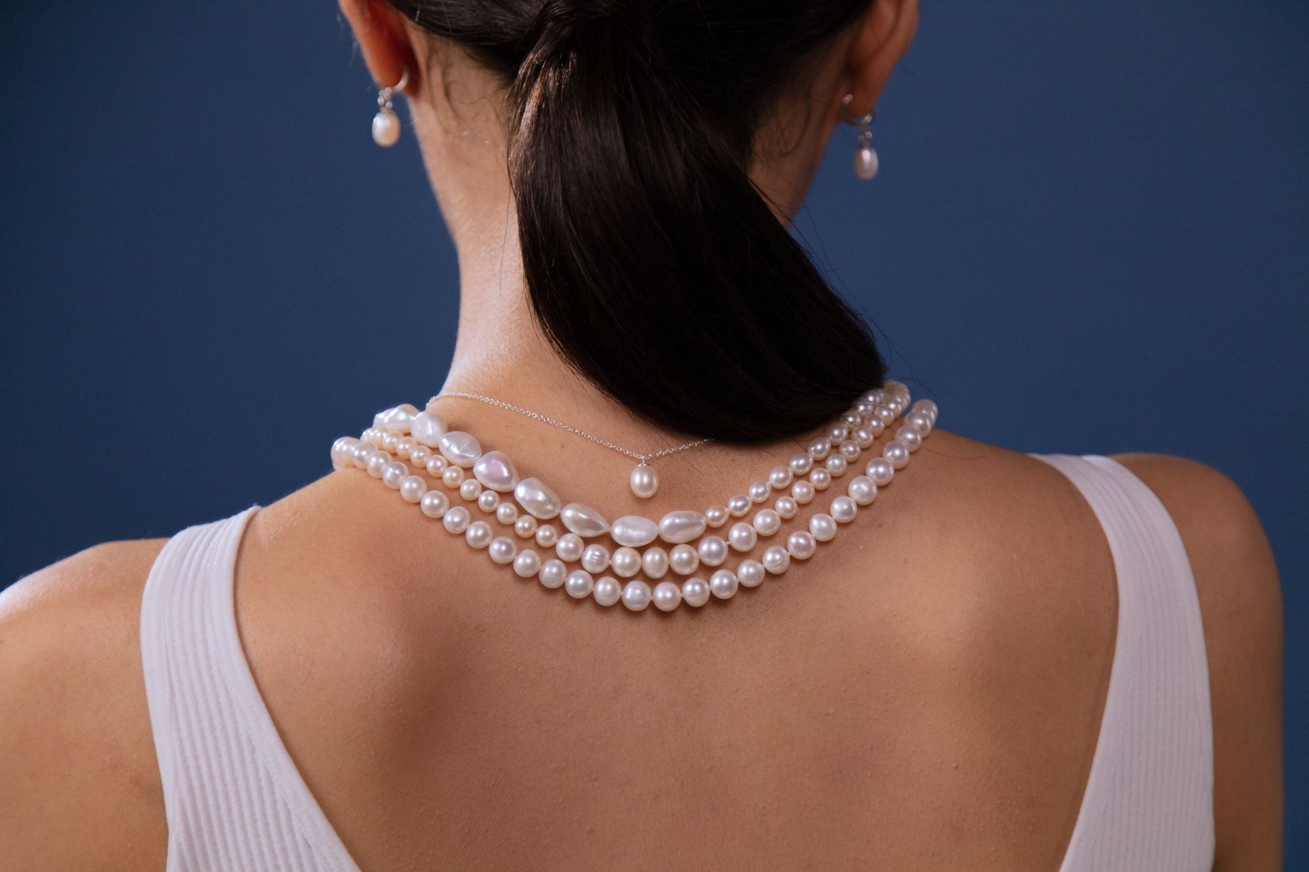 Fios de pérolas em camadas e brincos pendentes compõem look de joalheria, em referência às pérolas Akoya da coleção