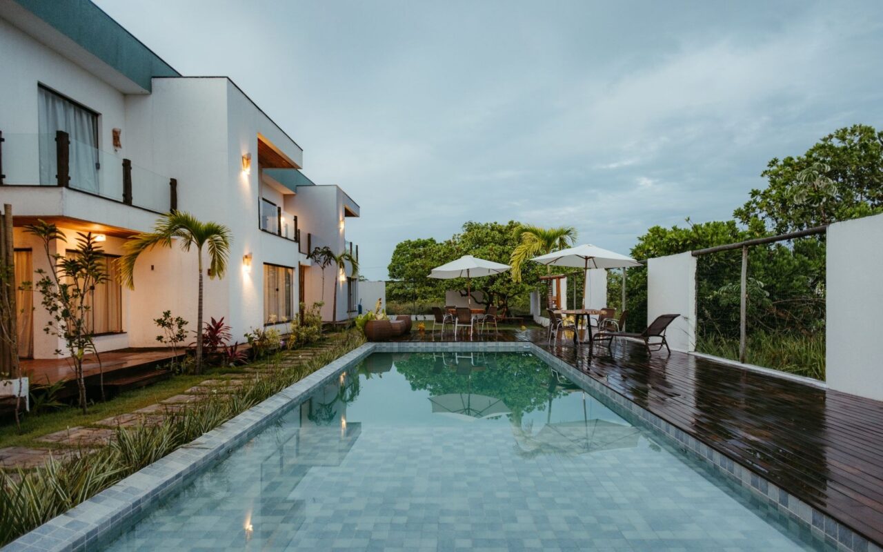 Casa contemporânea com piscina e deck de madeira ao entardecer, exemplo de villa de alto padrão no litoral