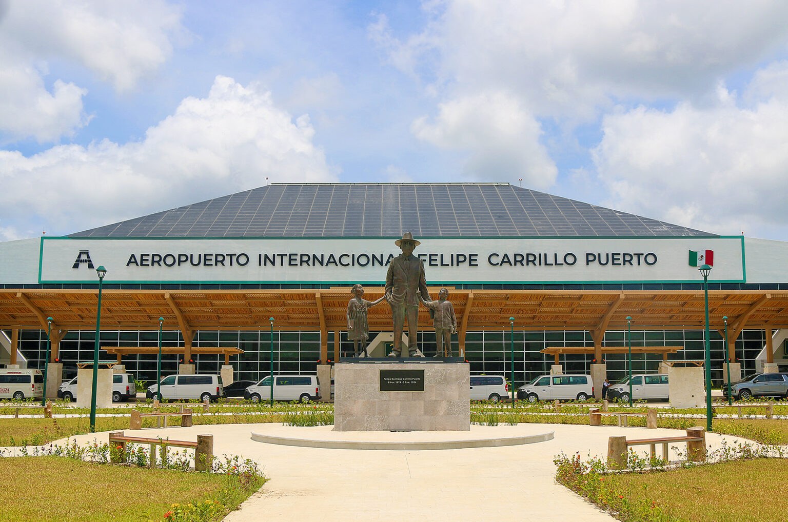 Uma estátua de bronze recebe quem desembarca no terminal, de telhado inclinado e jardins simétricos