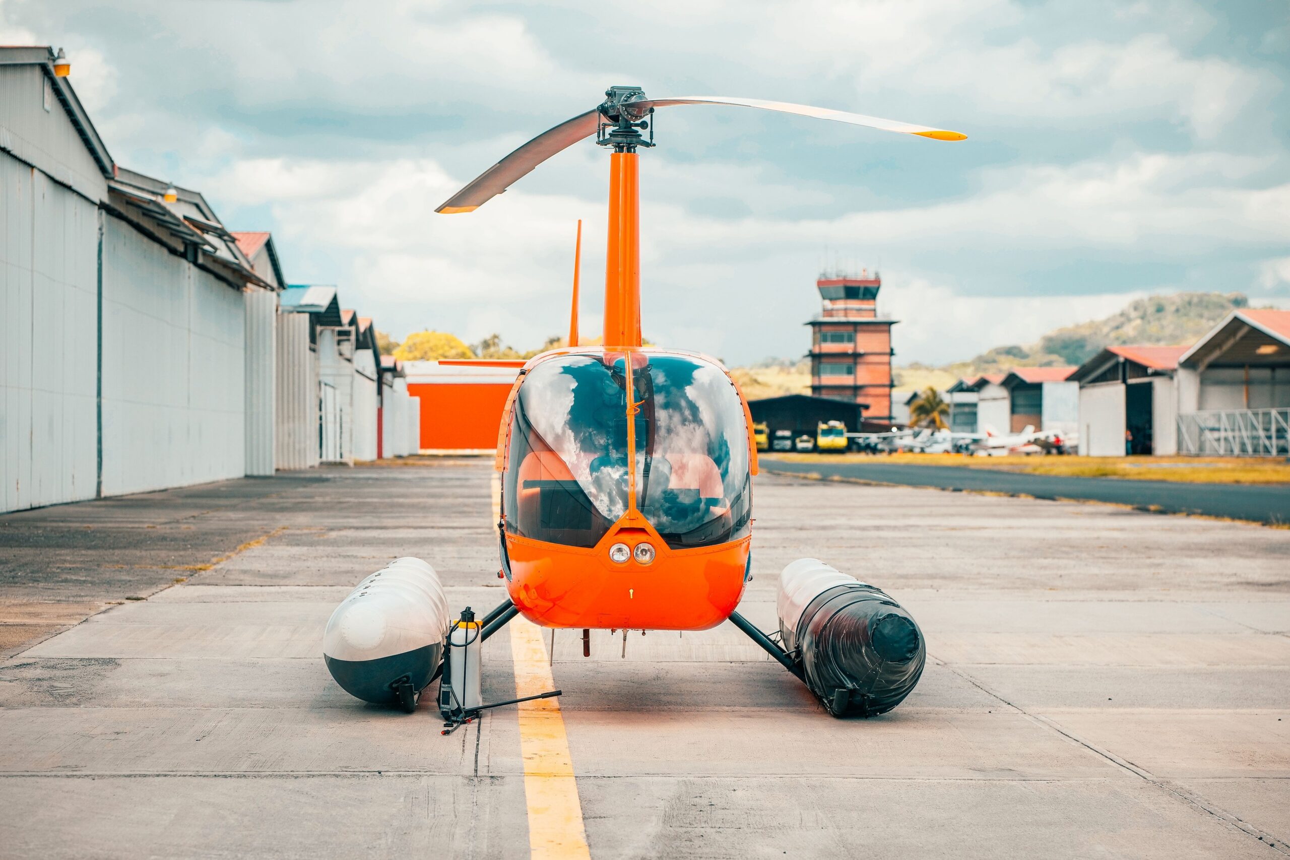 Hangares e torre de controle ao fundo mostram a estrutura que sustenta operações de asa rotativa