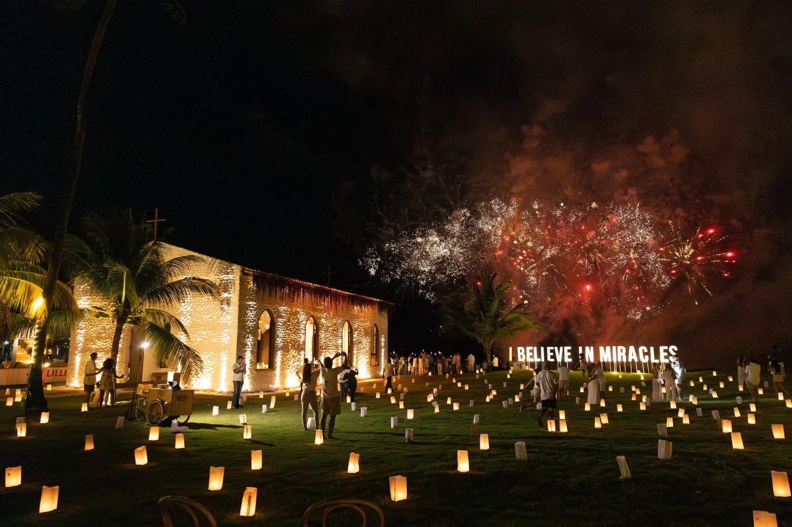 Centenas de luminárias de papel desenham o caminho até a capela, com fogos ao fundo