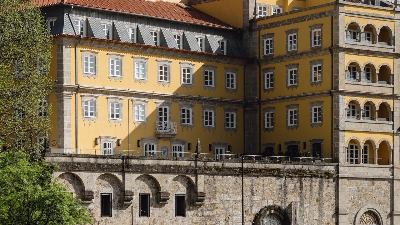 Fachada amarela de edifício histórico com arcadas e muro de pedra, em Amarante, no roteiro pelo Norte de Portugal