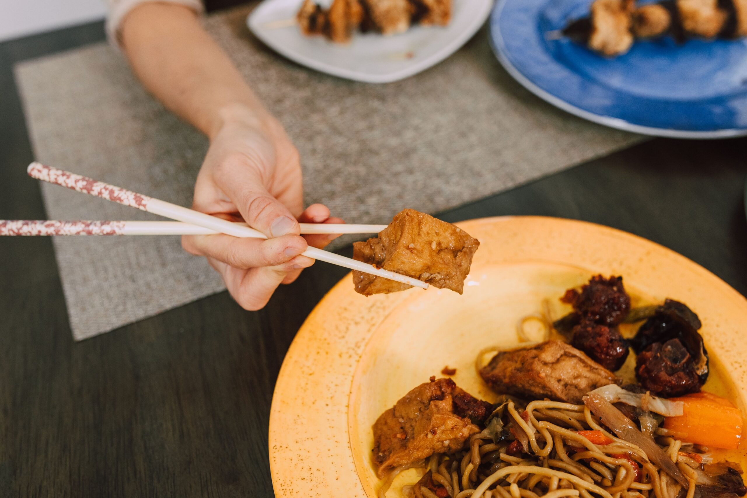 Cubos dourados, macios por dentro, servidos com macarrão e cogumelos à moda oriental