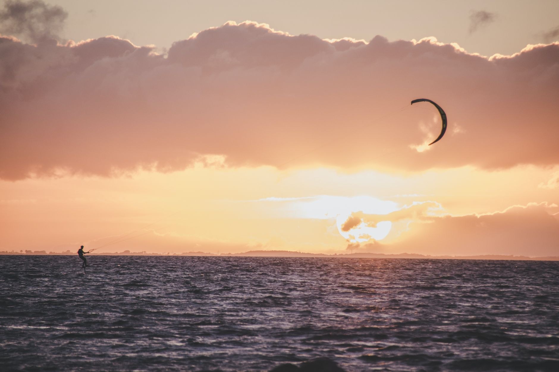 Praticante de kitefoil desliza ao entardecer, imagem que ilustra os esportes de vento do litoral cearense