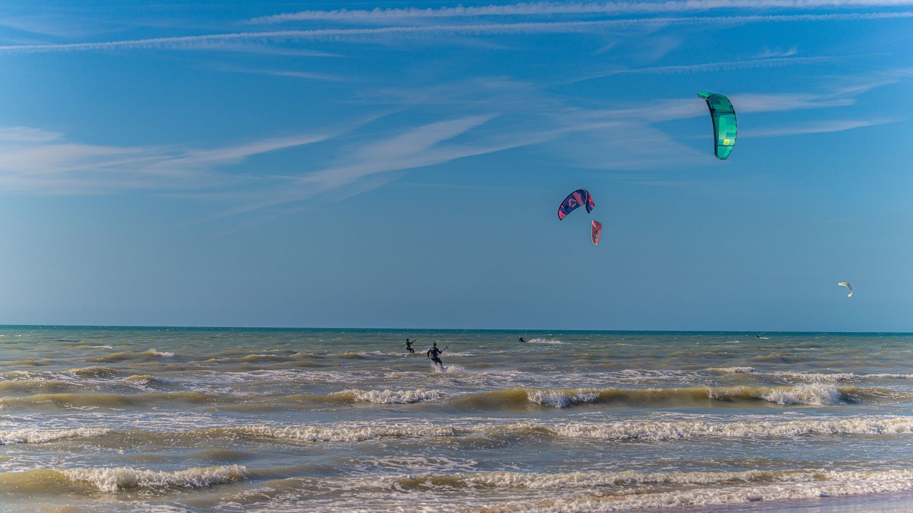 Kitesurfistas manobram sob céu azul, imagem que ilustra os esportes de vento praticados no litoral cearense